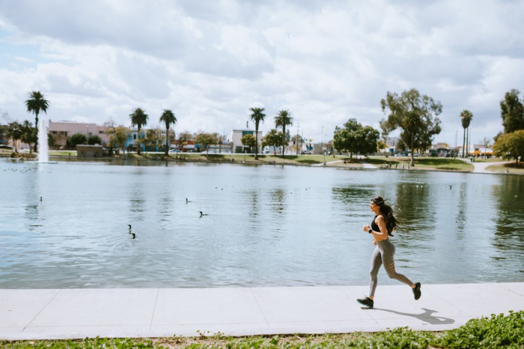 woman running next to pond with palm trees