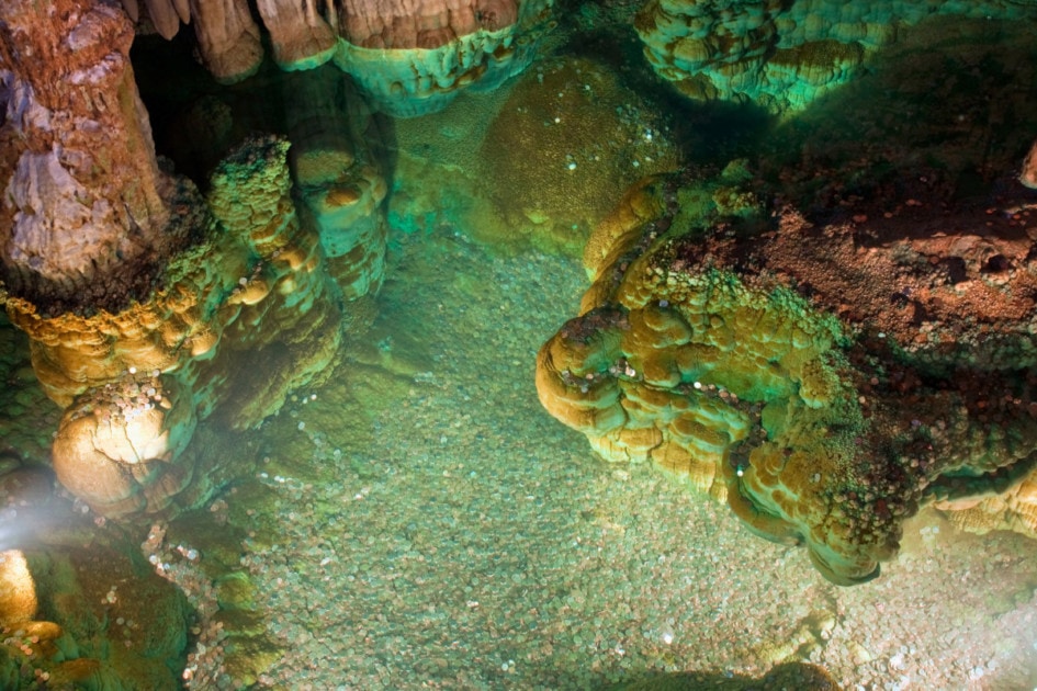 Long exposure shot taken in Luray Caverns in Virginia. The beautiful stalactites, stalagmites and flowstone makes this under ground geological cave a marvelous spectacle. The limestone geological formations are great in this subterranean marvel in the in the Shenandoah Valley.This underground pool has made the stones turn green as the acidic water has affected all the coins that people have thrown into the cavern water. - A great Background Texture Pattern, or Graphic Element Wallpaper for poster design.