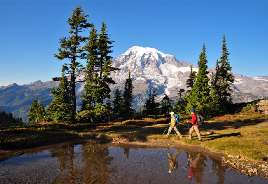 Two hikers walk by a small pond in Mt. Rainier National Park