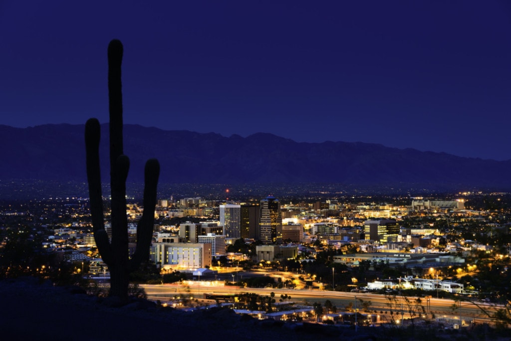 Tucson Arizona at night framed by saguaro cactus and Santa Catalina Mountains