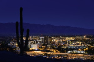 Tucson Arizona at night framed by saguaro cactus and Santa Catalina Mountains