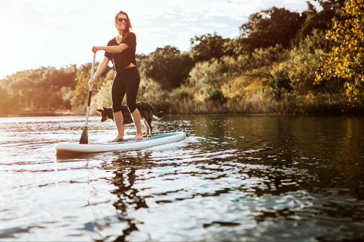 A woman paddleboarding with a dog