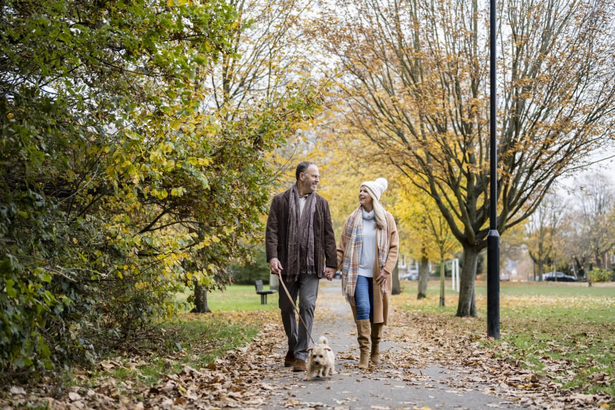 couple walking terrier on footpath in public park _ getty