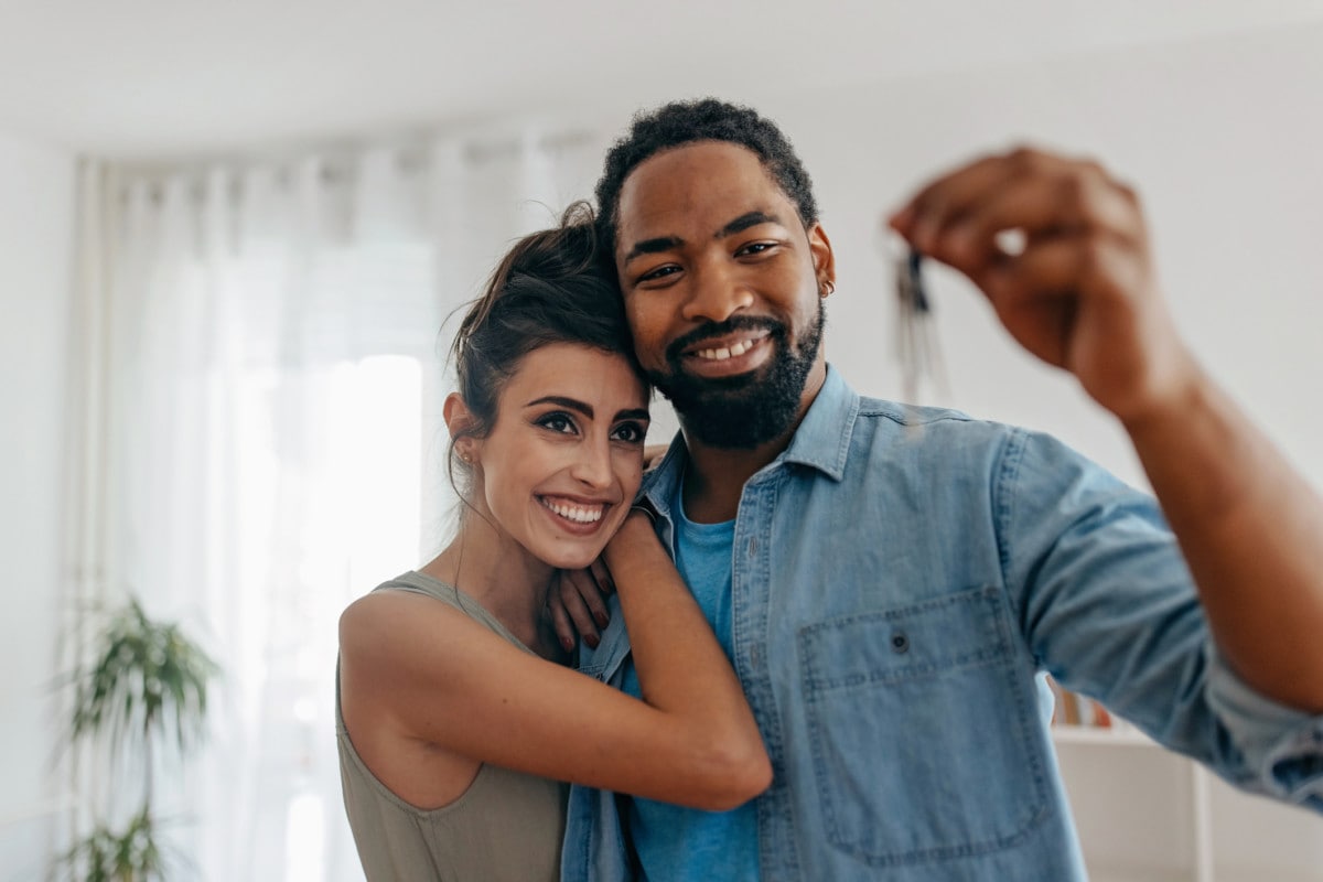 Couple holding up keys to house after completing all the steps to buying a home