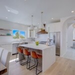 white bright kitchen with new appliances and orange barstools