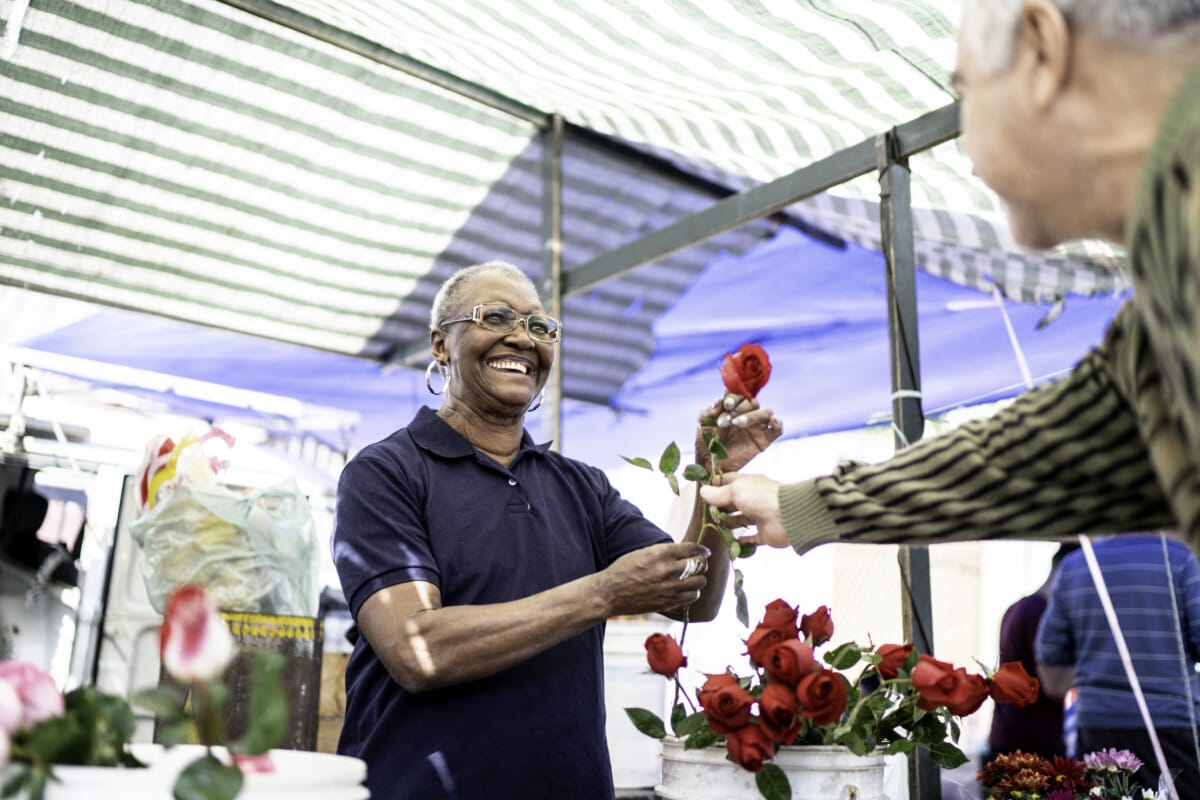 Senior florist selling a rose to client