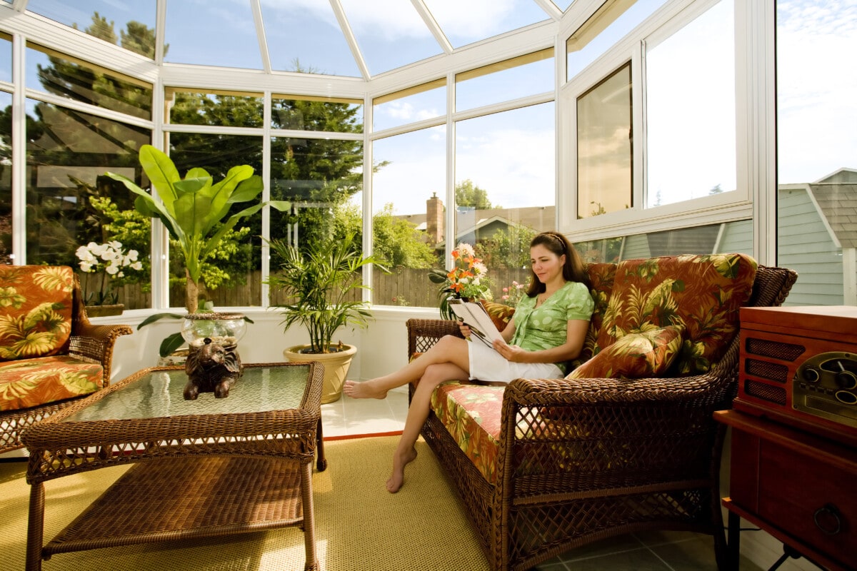 Woman reading a book in a nicely decorated Southern sunroom