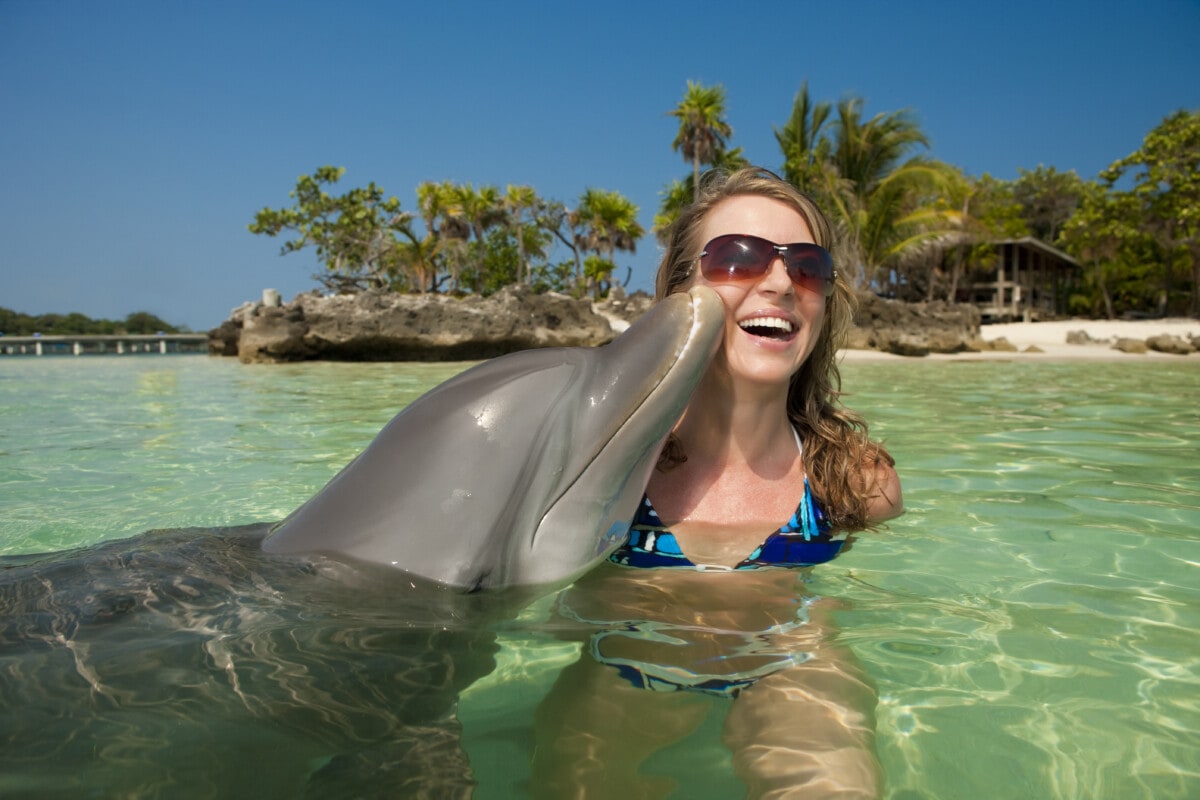 A dolphin swimming with a woman in tropical waters
