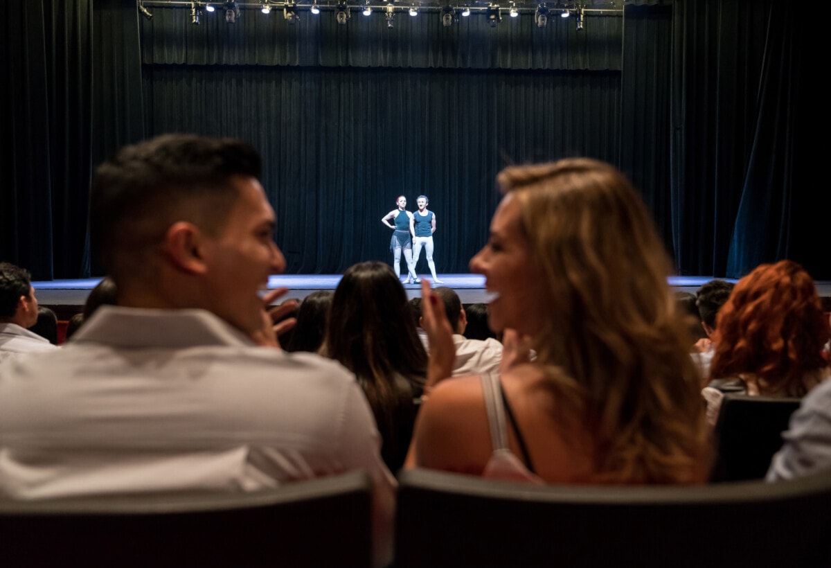 Young couple on a date at ballet applauding and looking at each other smiling