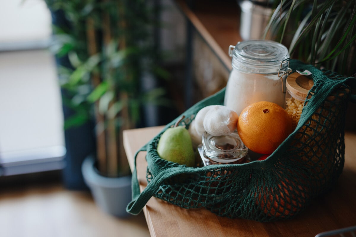 Eco bag on kitchen counter with food in jars and fresh fruits. Zero waste concept 