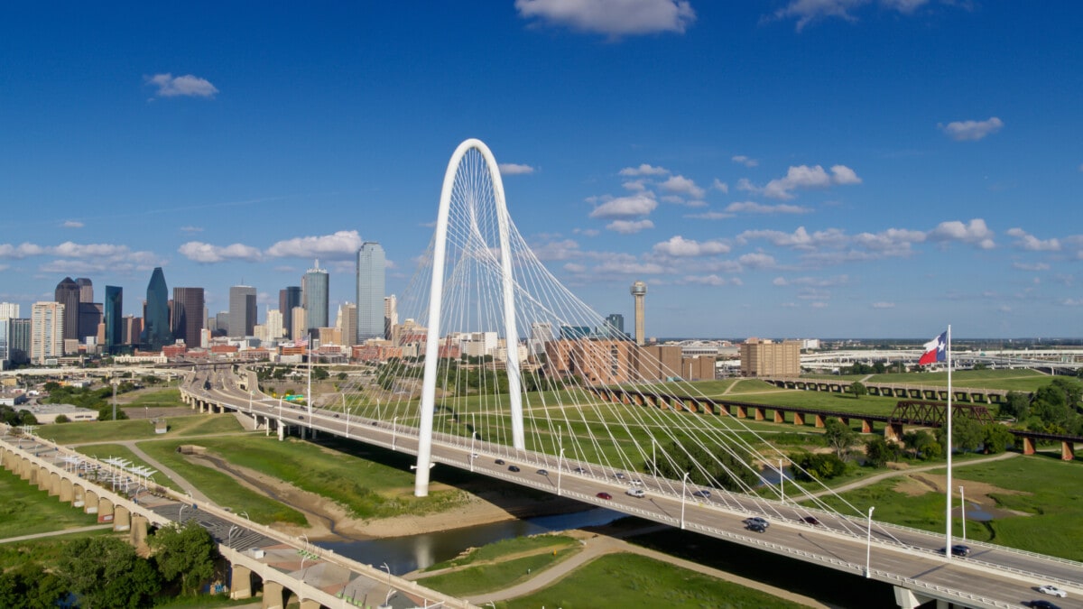 Drone Shot of Texas State Flag Waving Over Margaret Hunt Hill Bridge with Dallas Skyline