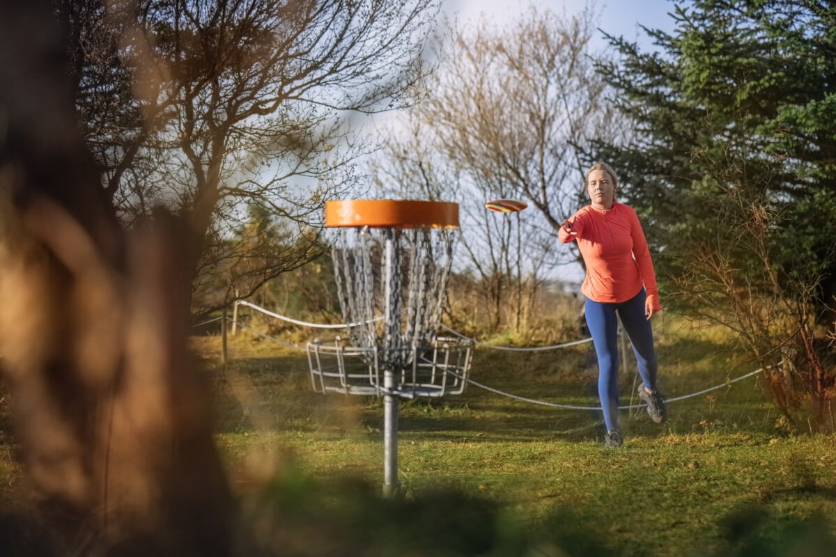 Woman putting during a game of disc golf in 
