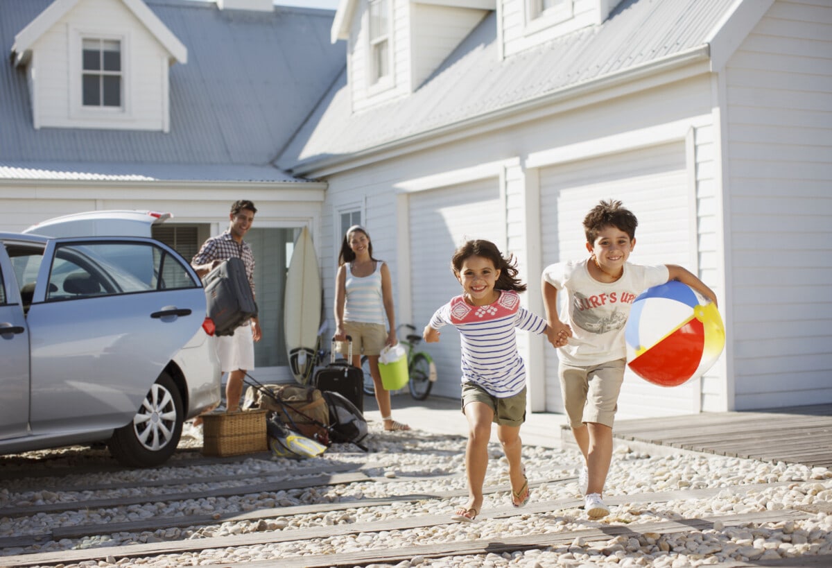 Brother and sister with beach ball running on driveway