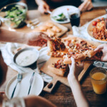 close up of pizza and other light appetizers being shared amongst a group of people