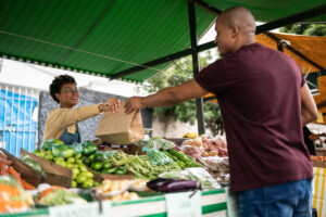 Seller handing the shopping bag to a customer at a street market