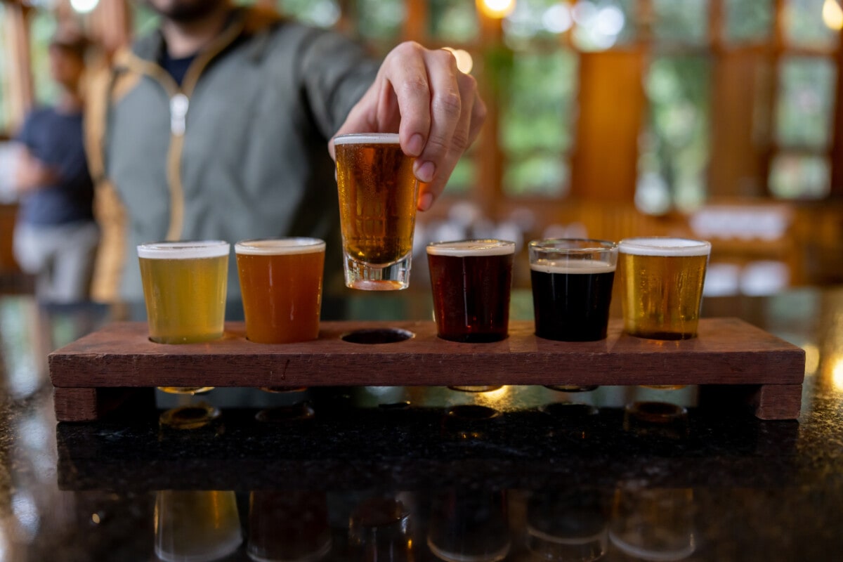 Close-up on a man trying beers from a sampler while taking a tour at a brewery