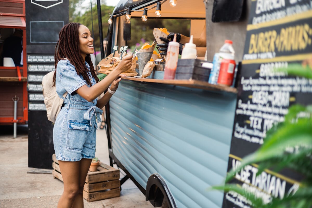 woman buying fast food at food truck on the street