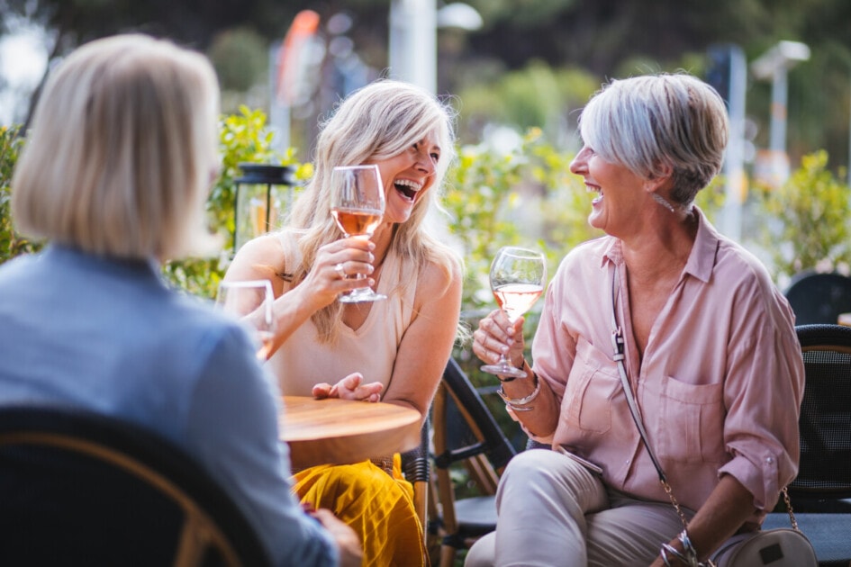 Women drinking wine and laughing together at restaurant