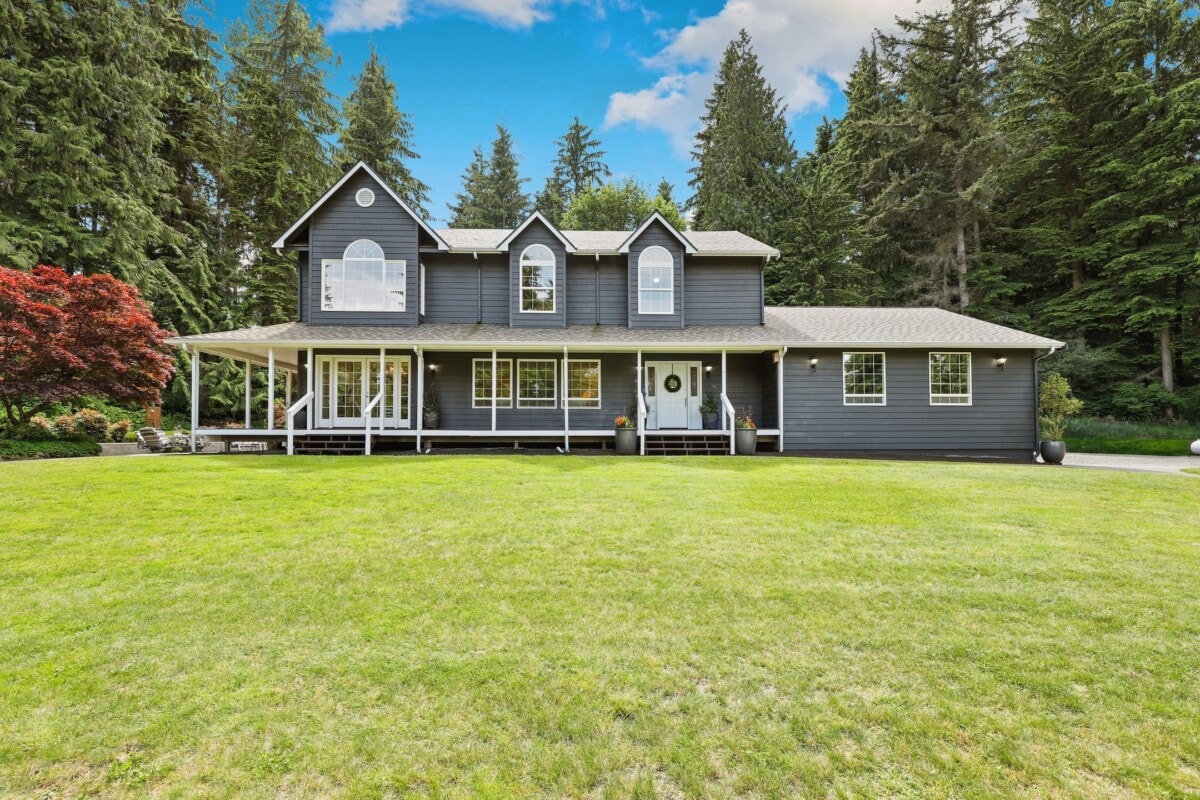gray farmhouse with large front porch and yard