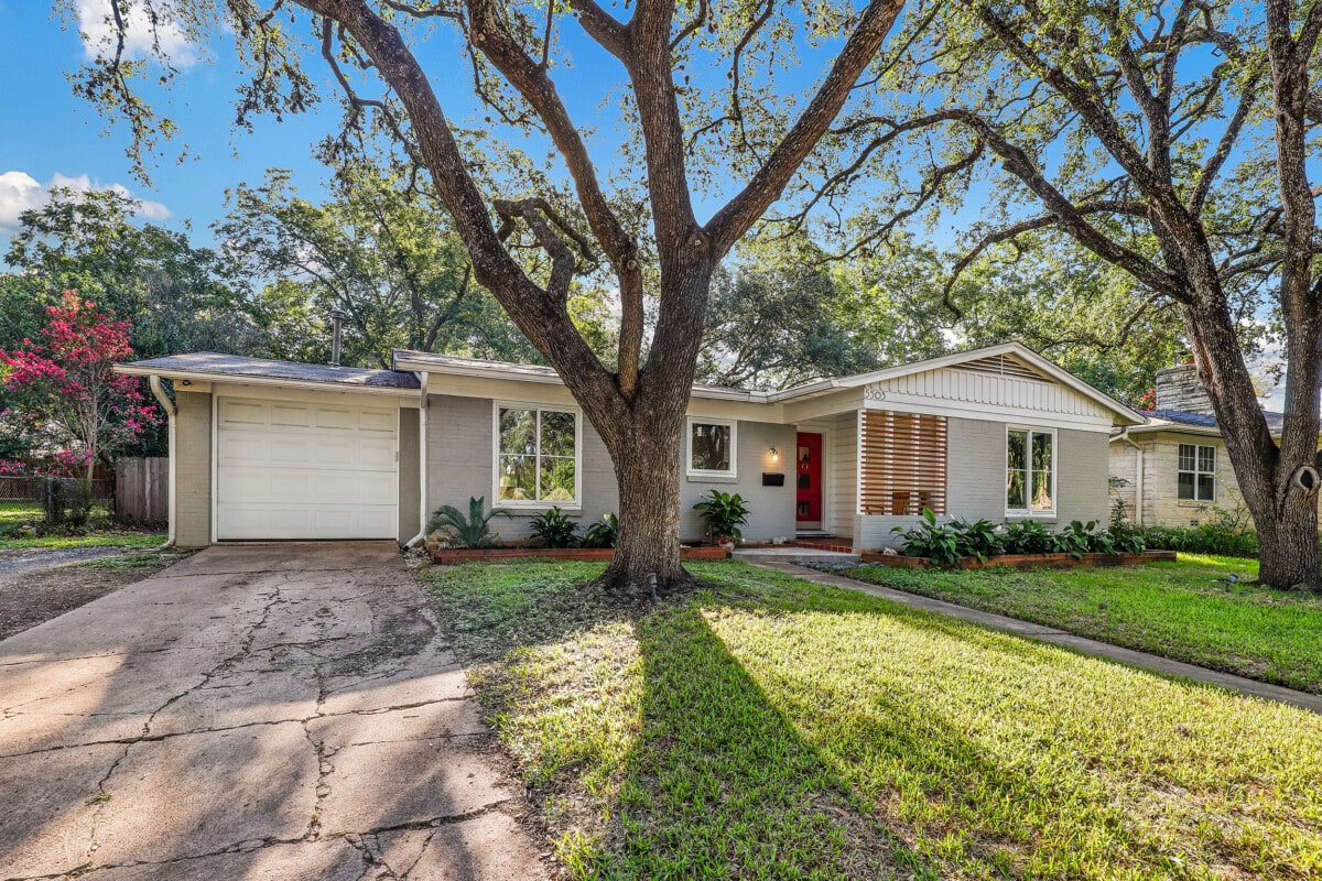 rambler style home with large tree in the yard