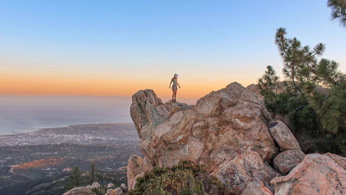 woman standing on rocks in rock garden with the ocean in the background