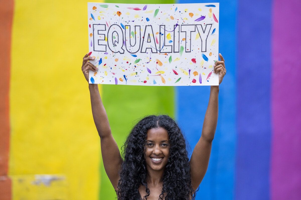 Woman holding up a poster that says equality
