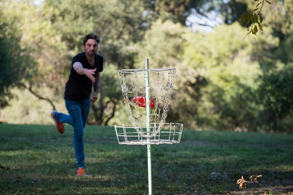 Disk golfer takes a shot towards the disk cage