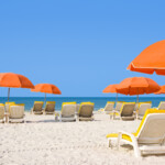 White sandy beach with lounge chairs and orange umbrellas