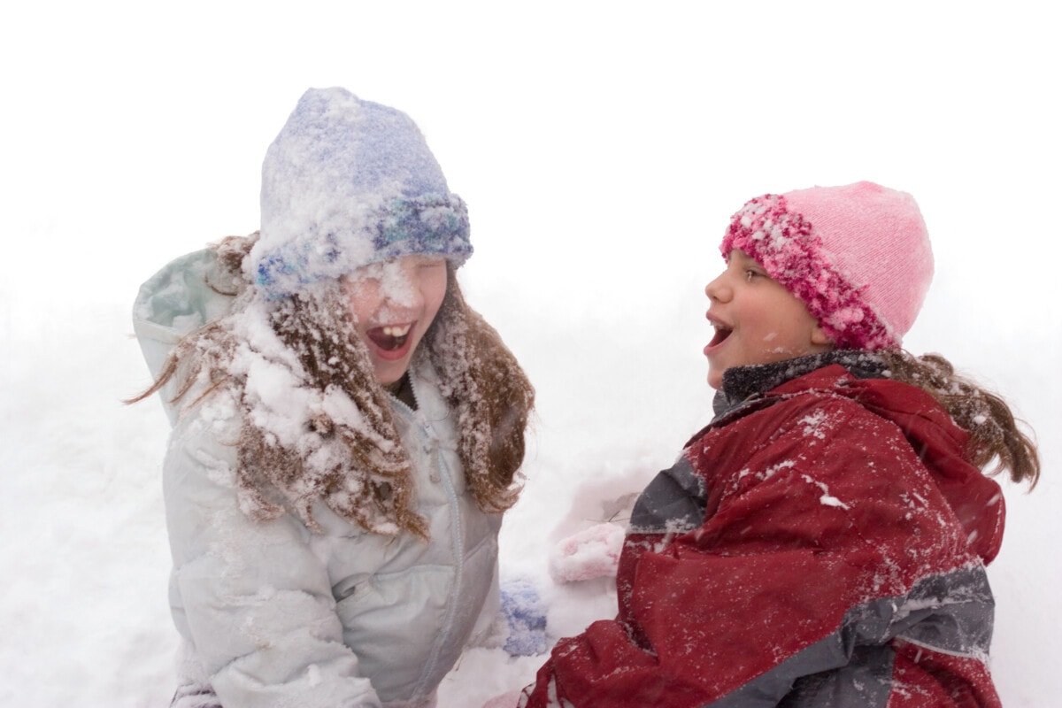 Two young girls are playing in the snow
