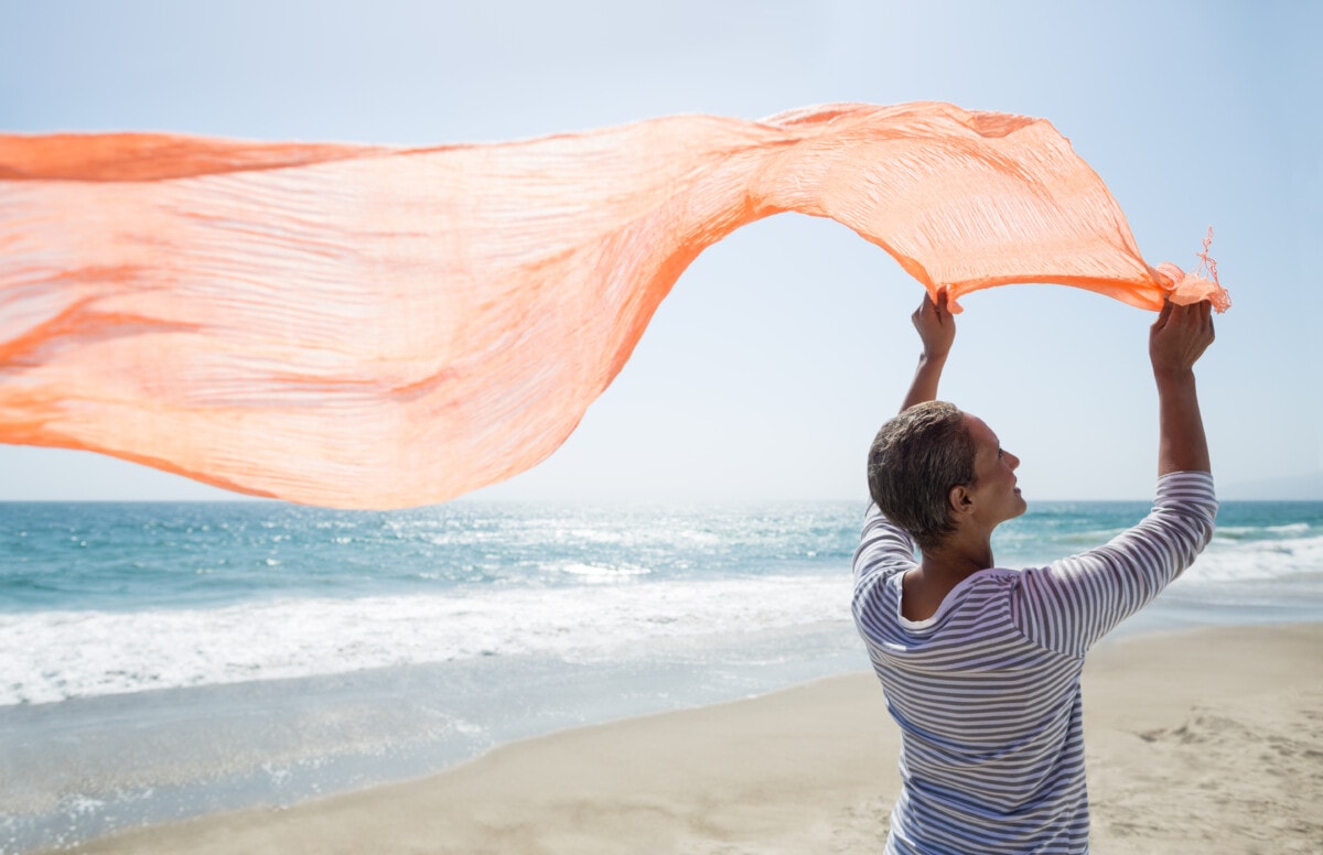 Woman standing on beach holding scarf