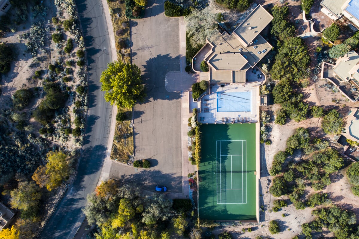 Villa med pool och tennisbana sett från himlen.