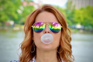 person in sunglasses blowing a bubble