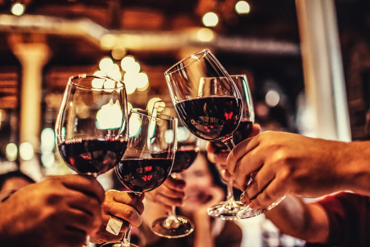 five glasses of red wine clinking during a celebratory toast