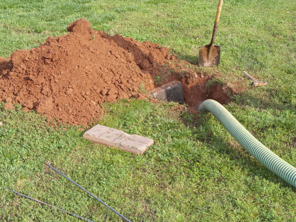 Seen here is a dug out open septic tank being pumped out.  All the required tools are laying in the yard.
