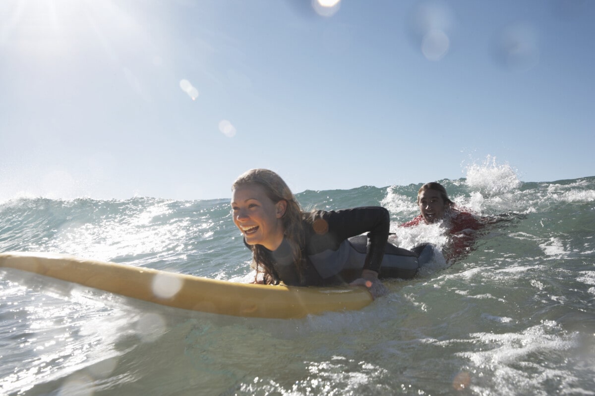 two people being towed on a surfboard in the ocean