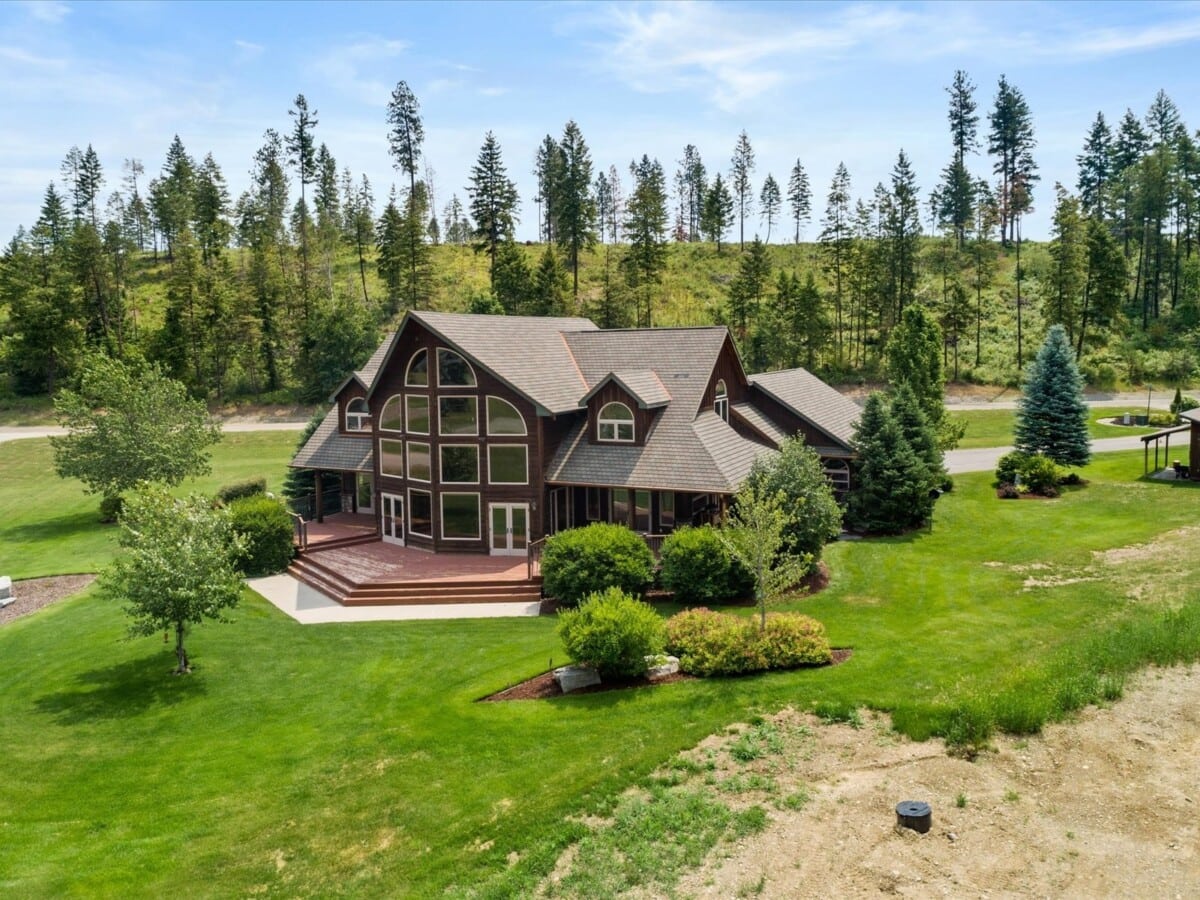 large brown home with windows surrounded by trees