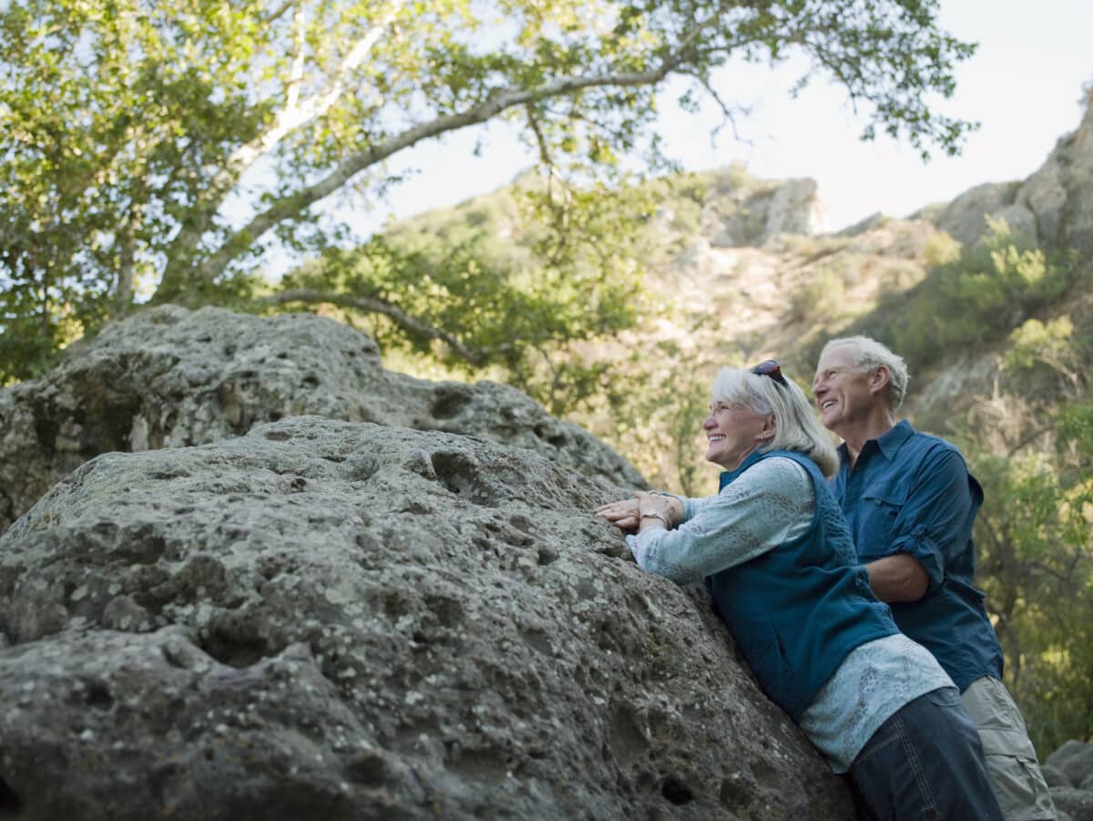 Mature couple leaning on large boulder