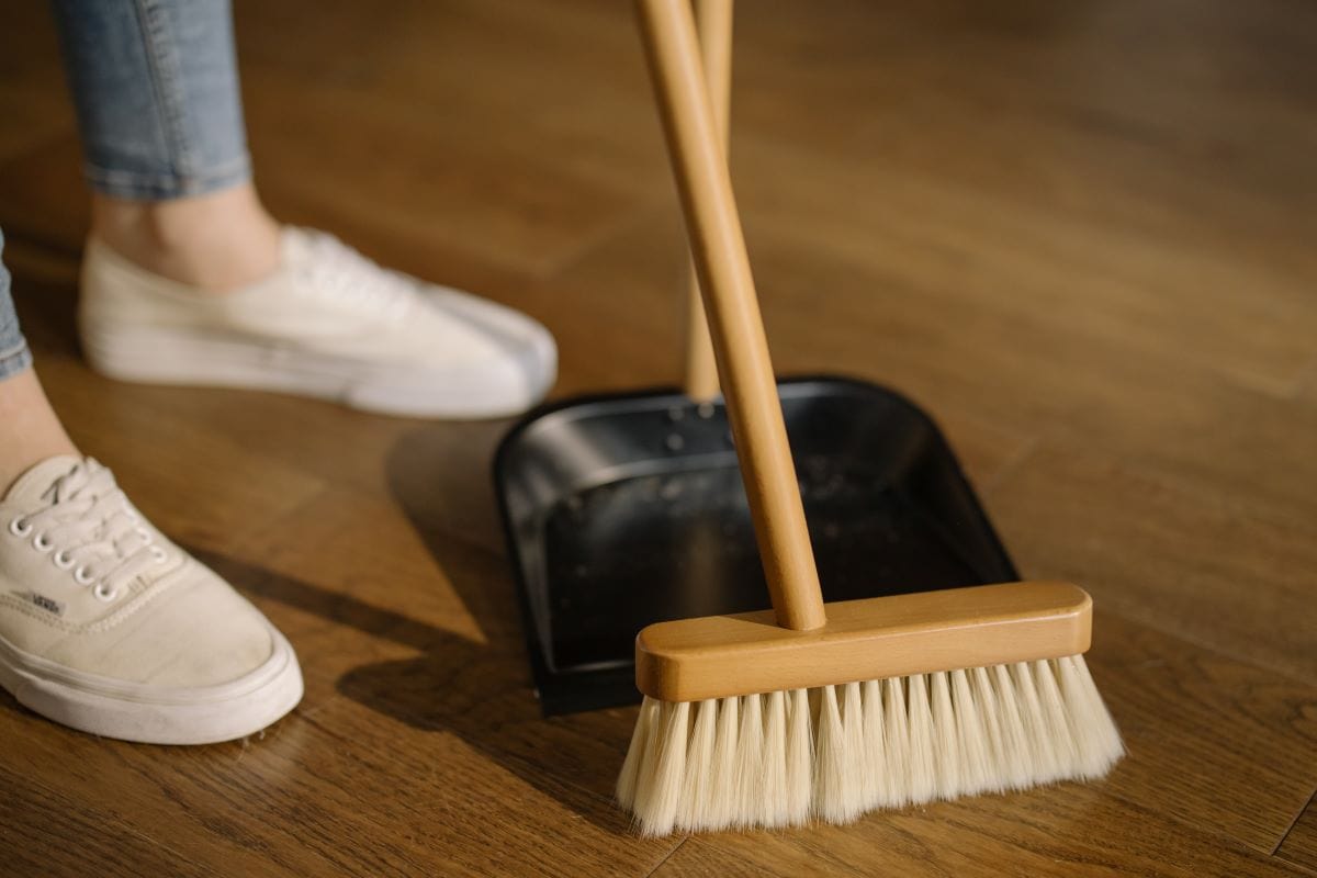 broom and black dust pan on a wood floor