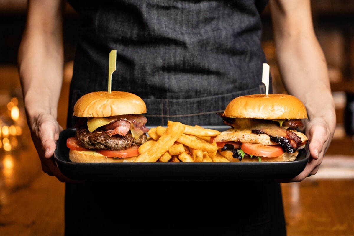 Burgers and fries served on a platter by waiter