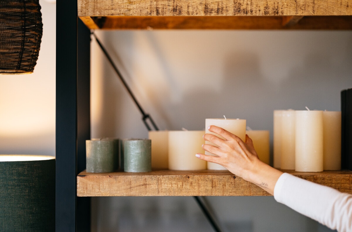 An anonymous businesswoman holding candle and arranging shelf while standing in the home decor store.