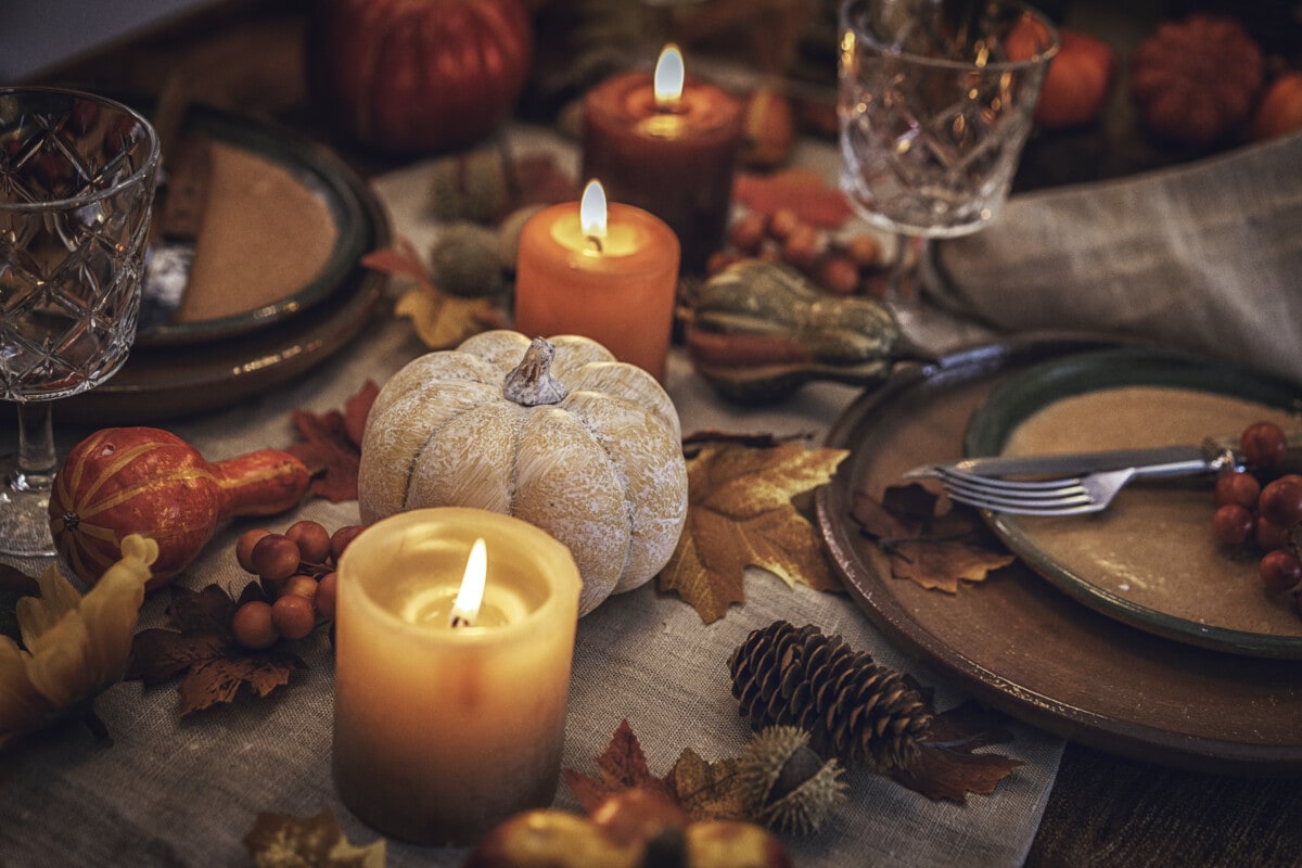 Decorated Table Setting for Thanksgiving Dinner with Candles, Pumpkins, Leafs and Nuts