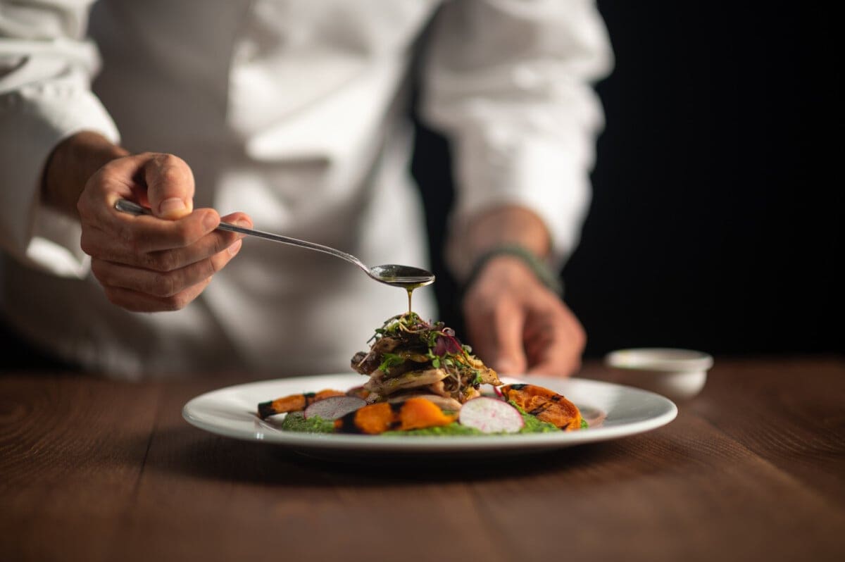 A chef pouring sauce on meal