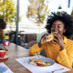 Woman enjoying eating sandwich at restaurant