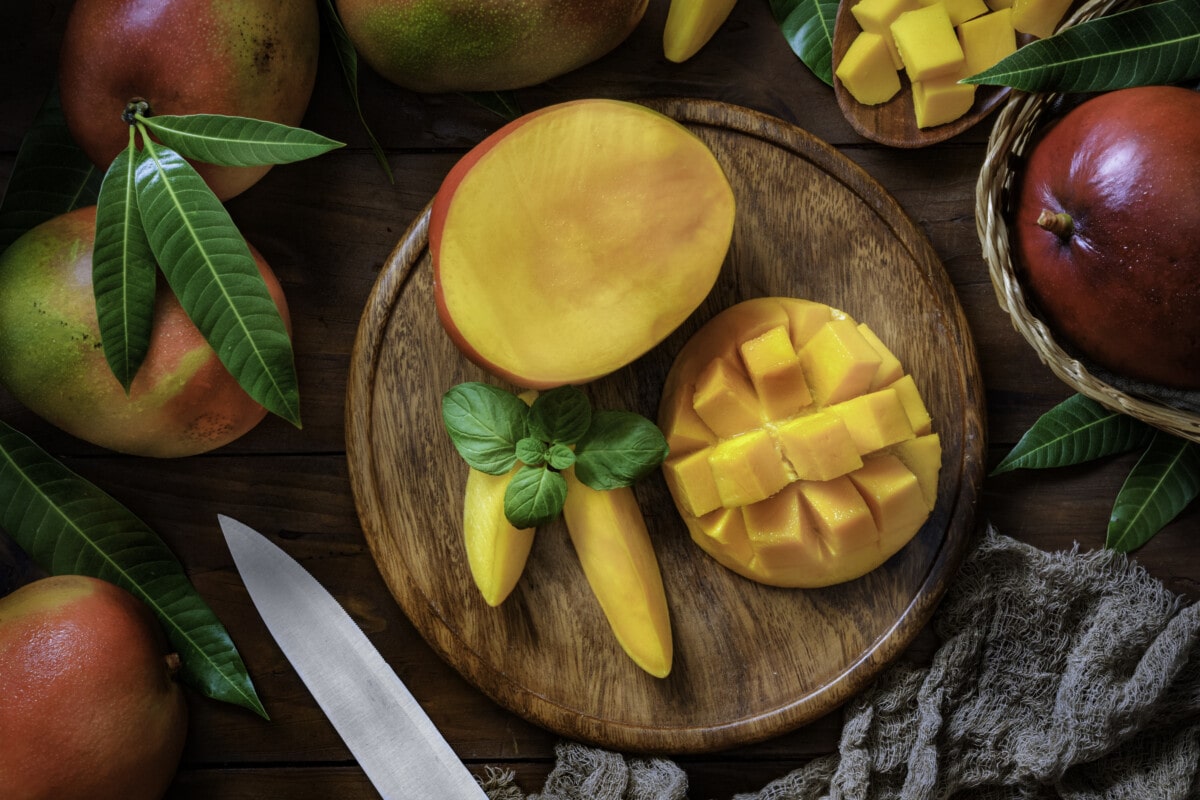 Healthy eating themes. Tropical Fruits: Sliced mangos in a wooden plate on a table in rustic kitchen
