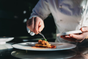 A chef is finishing the preparation of the plate. He's decorating the plate just before the serving.