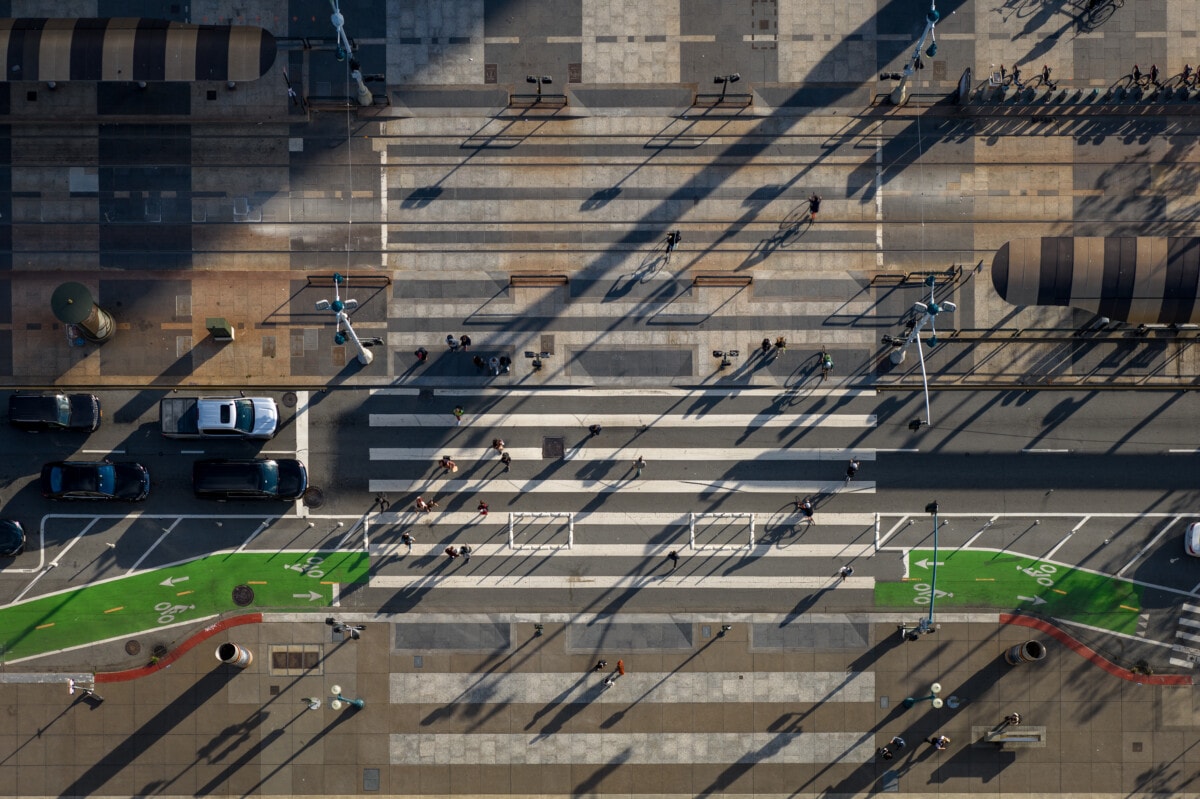 Aerial view of pedestrians walking on the Embarcadero crossing in San Francisco on a sunny afternoon.