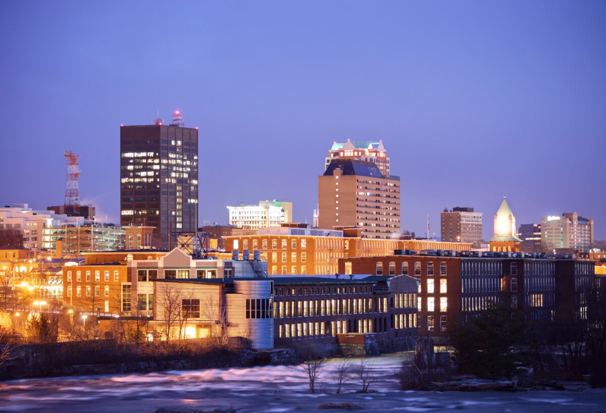 Manchester, New Hampshire skyline along the banks of the Merrimack River at night. Manchester is the largest city in the state of New Hampshire and the largest city in northern New England. Manchester is known for its industrial heritage, riverside mills, affordability, and arts & cultural destination.