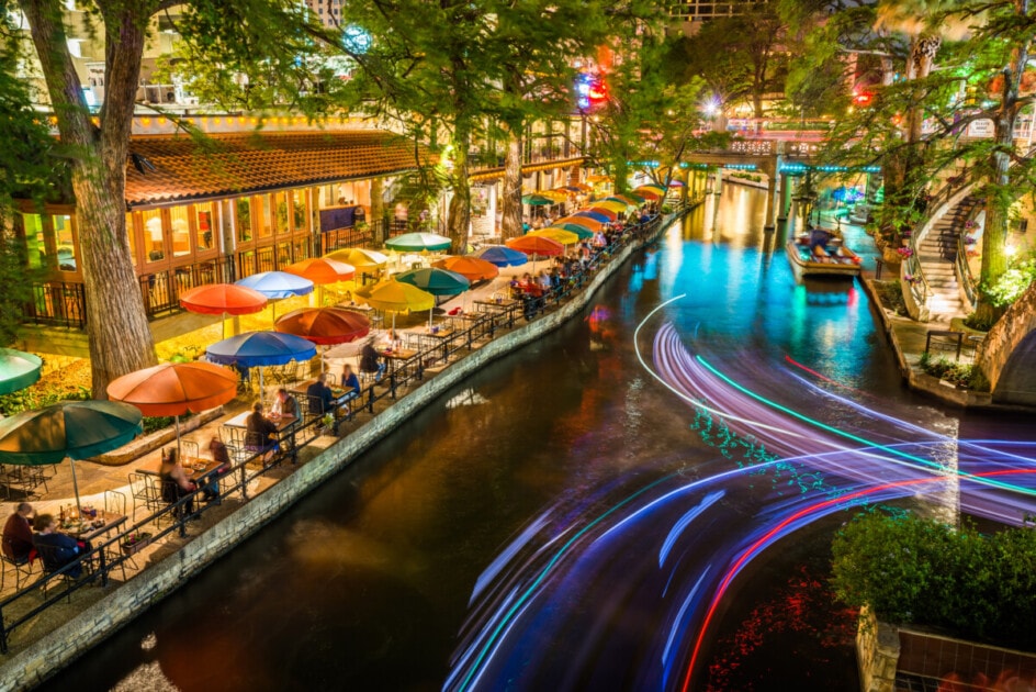 San Antonio Riverwalk - San Antonio Texas, Famous tourism park walkway along scenic river canal at night. Light trails from tour boats.