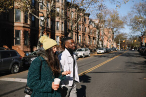 Friends walking down the street in Brooklyn, Park Slope district, having a coffee on the go.