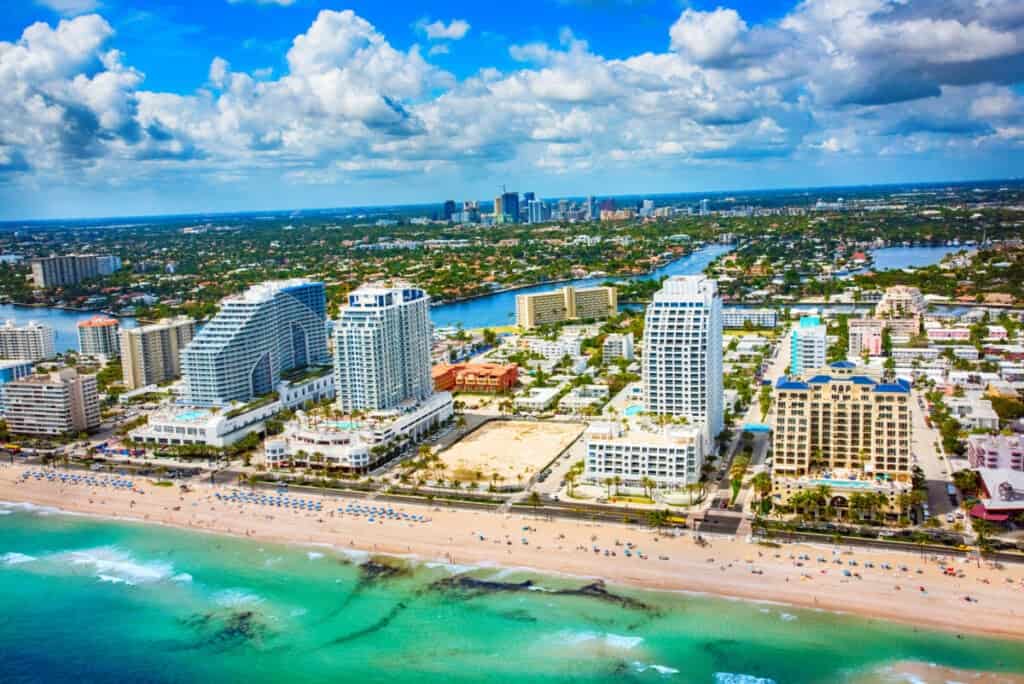 Aerial view of the hotels lining the beach in Fort Lauderdale, Florida with the skyline of downtown in the background.